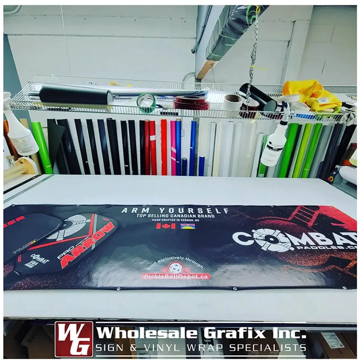 Coloured vinyl rolls racked in the Wholesale Grafix shop beside a freshly printed banner