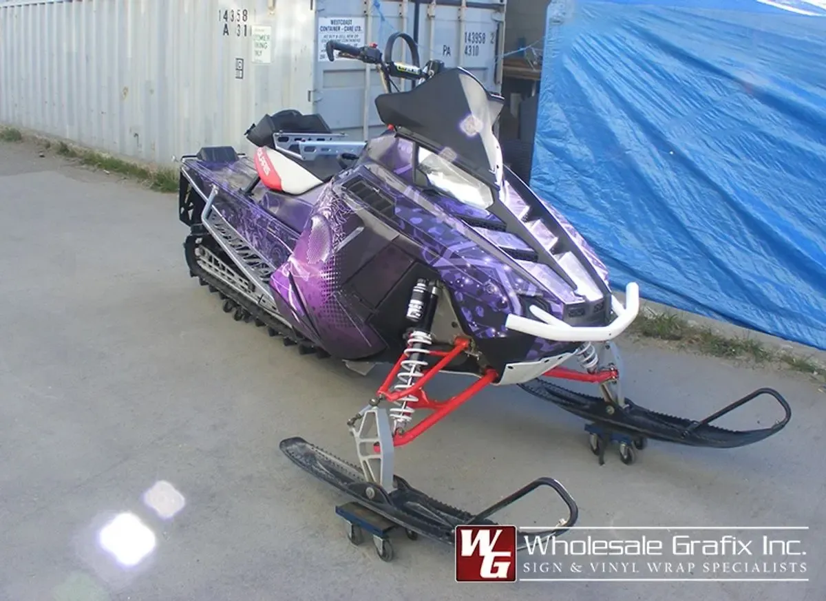 Wrapped snowmobile photographed against a printed backdrop in the shop