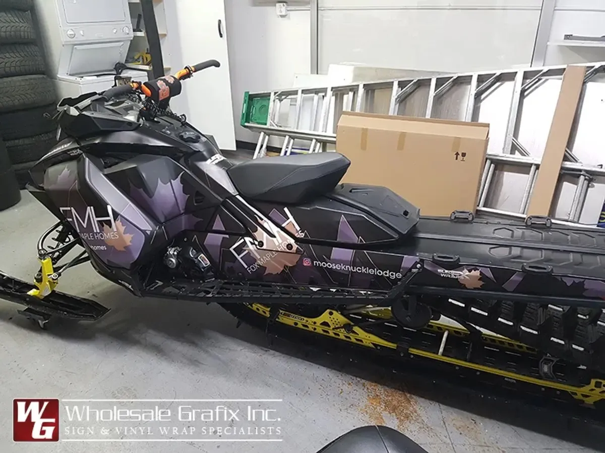 Mooseknuckle Lodge branded snowmobile in a matte black wrap