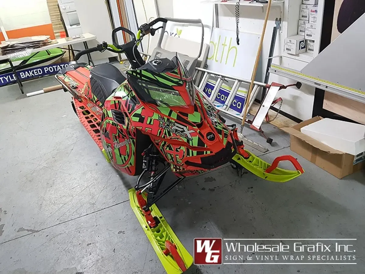 Snowmobile in a red and teal graffiti-style art wrap